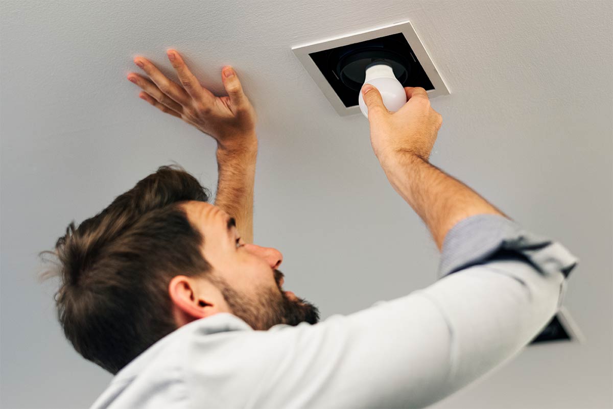 Man installing a lightbulb in a ceiling light