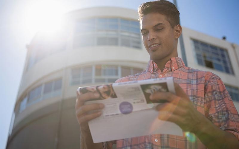 Smiling man looking at commercial real estate listings outside